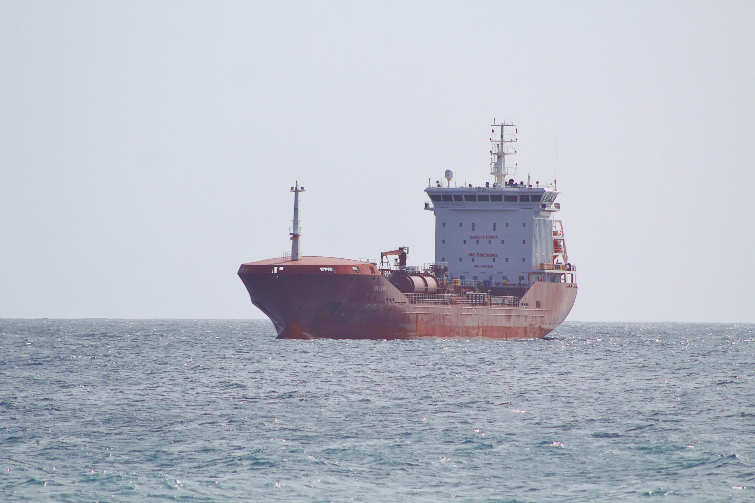 Huge cargo ship sailing on the ocean under clear skies, conveying maritime transport.